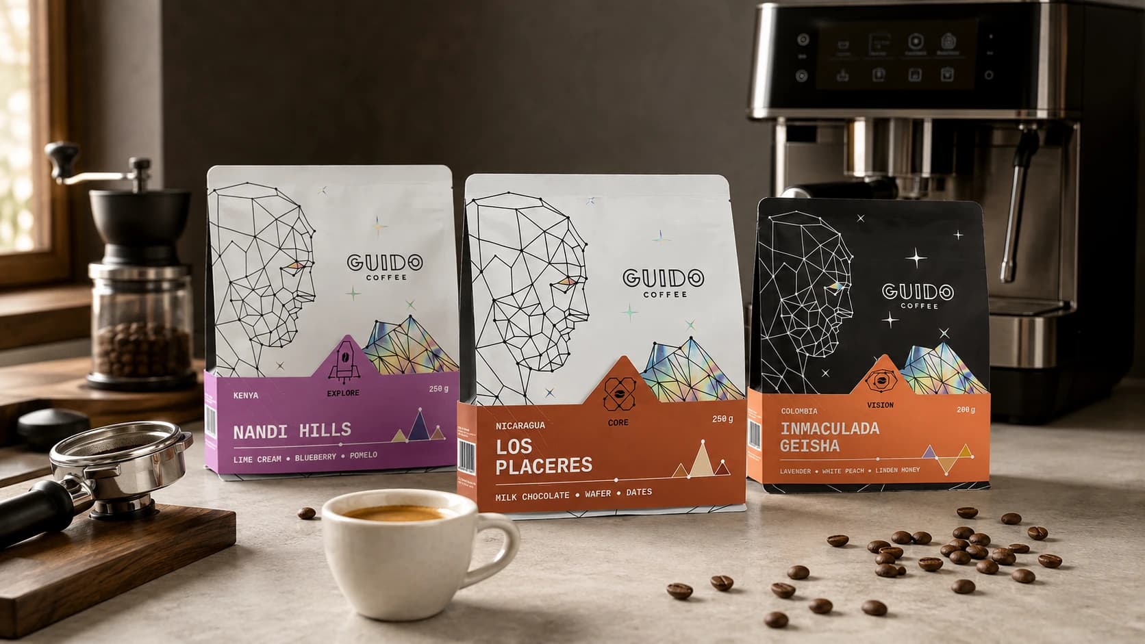 Trei pungi de cafea Guido langa un espressor, o rasnita, un portafiltru si o ceasca de espresso